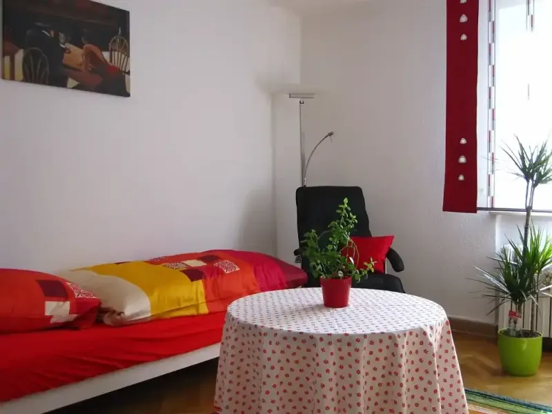 einzelschlafzimmer mit bett tisch stehlampe und relaxsessel sowie grosser zimmerpflanze1
